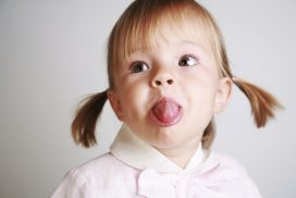 Una niña con coletas saca la lengua en gesto burlón, metáfora del niño rebelde según el análisis transaccional. 