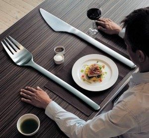 Comensal en una mesa con cubiertos exageradamente grandes y un plato pequeño; peligro de las dietas para adelgazar rápido 