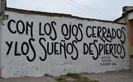 Graffiti en una pared: "con los ojos cerrados y los sueños despiertos"