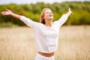 Una mujer con los brazos abiertos y rostro sonriente, es posible liberarnos y adelgazar sin dietas estrictas que nos malhumoren