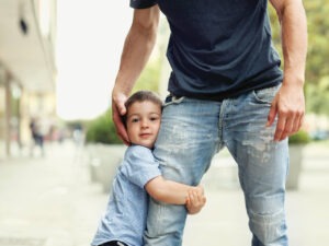 Un niño se abraza a la pierna de su padre, parece decir:  mi padre y yo