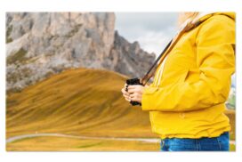 Una mujer explorando con prismáticos un paisaje natural, como antes de decidir un proceso de coaching o psicoterapia