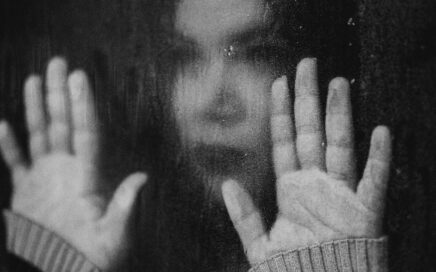 Rostro de una mujer tras una ventana húmeda, se percibe mal como si, metafóricamente, estuviera bajo la luz de gas emocional
