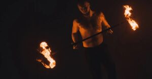 Un hombre sostiene una barra con dos fuegos. Es una práctica ritual típica de los grupos mitopoéticos de las masculinidades críticas. 