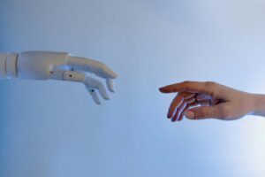 Una mano humana y otra robótica a punto de tocarse. 