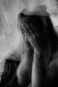 El torso difuminado de una mujer que se lleva las manos a la cara