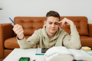 Muchacho conectado al ordenador y con cara de estresado. 