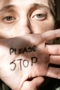 Mujer con palabras en la mano "please stop"