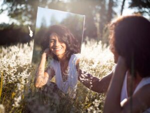 Una mujer joven se refleja en un espejo con naturalidad,  tal y como es y sonriendo