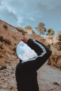 Un hombre lleva un espejo que no le refleja a él, contrariamente a lo que sí hacen las afirmaciones positivas poderosas y realistas