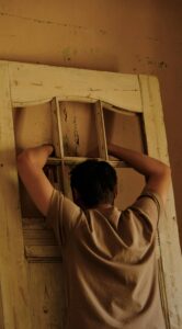 Un hombre manipulando con ambas manos unos adornos de una puerta. 