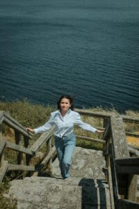 Una mujer sube unas escaleras que ascienden desde el nivel del mar a algún lugar elevado. 