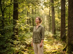 Una mujer de pie en un bosque parece estar aceptando la realidad que la rodea.